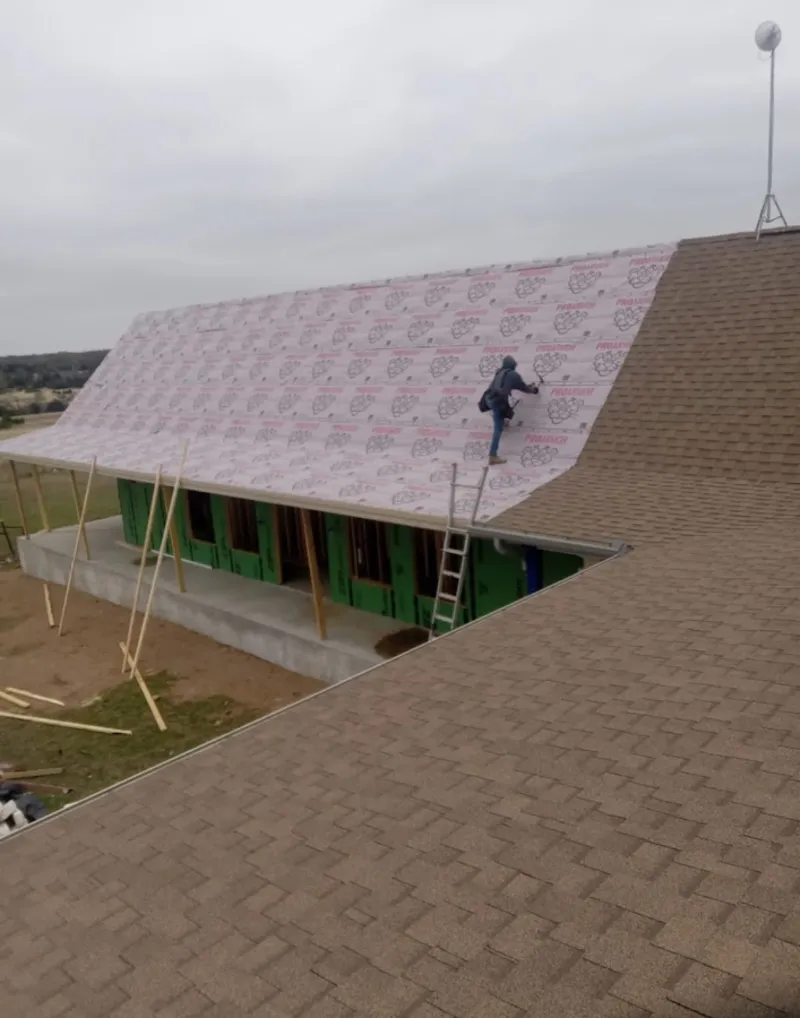 Worker preparing underlayment for a metal roof installation in Trenton